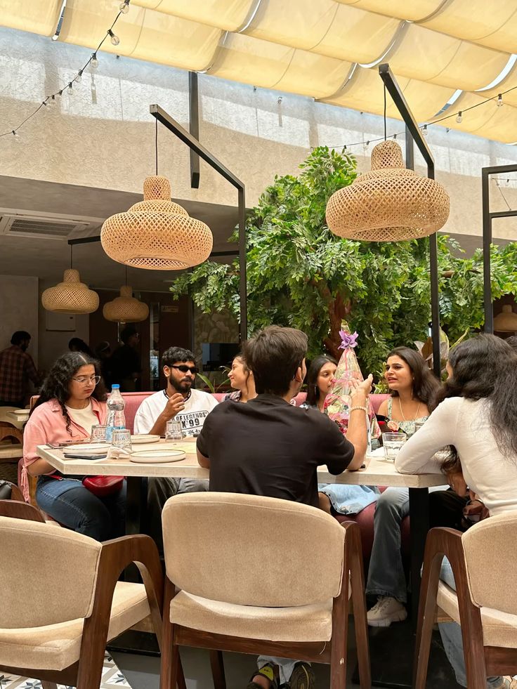 Group of Indian friends communicating and enjoying cafe food and drinks